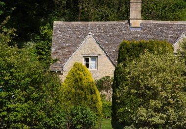 Tipik Cotswolds 'daki küçük evler küçük Bibury kasabasının sokaklarını süslüyor.