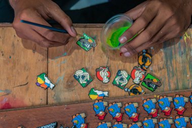 Emaye boyası kullanılarak yapılan akrilik ve rengarenk iğne işçiliğinin ayrıntıları, temizlikten boyamaya kadar tüm işlemler küçük bir ev atölyesinde yapılır.