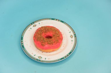 Donuts made by a home industry with the basic ingredients of palm sugar with various kinds of toppings such as chocolate, strawberries, green tea, and sprinkles. photographed flat served on a plate and a turquoise background