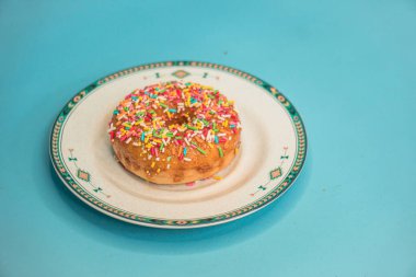 Donuts made by a home industry with the basic ingredients of palm sugar with various kinds of toppings such as chocolate, strawberries, green tea, and sprinkles. photographed flat served on a plate and a turquoise background