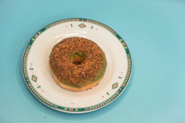 Donuts made by a home industry with the basic ingredients of palm sugar with various kinds of toppings such as chocolate, strawberries, green tea, and sprinkles. photographed flat served on a plate and a turquoise background