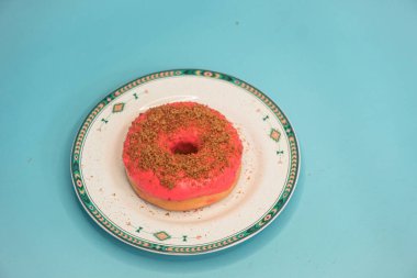 Donuts made by a home industry with the basic ingredients of palm sugar with various kinds of toppings such as chocolate, strawberries, green tea, and sprinkles. photographed flat served on a plate and a turquoise background