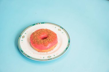 Donuts made by a home industry with the basic ingredients of palm sugar with various kinds of toppings such as chocolate, strawberries, green tea, and sprinkles. photographed flat served on a plate and a turquoise background