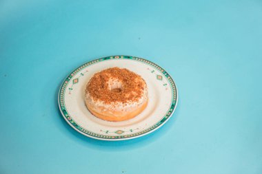 Donuts made by a home industry with the basic ingredients of palm sugar with various kinds of toppings such as chocolate, strawberries, green tea, and sprinkles. photographed flat served on a plate and a turquoise background