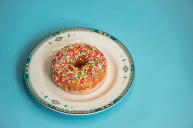Donuts made by a home industry with the basic ingredients of palm sugar with various kinds of toppings such as chocolate, strawberries, green tea, and sprinkles. photographed flat served on a plate and a turquoise background