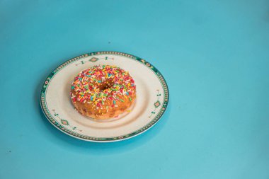 Donuts made by a home industry with the basic ingredients of palm sugar with various kinds of toppings such as chocolate, strawberries, green tea, and sprinkles. photographed flat served on a plate and a turquoise background