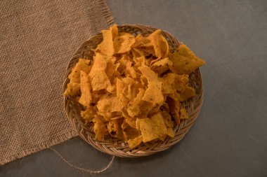 Tortilla chips served in a bamboo basket with a flat lay concept, the tortilla chips are fried golden yellow and very crunchy