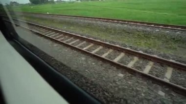 Pencere kenarında oturan trene bin. Pencerenin dışındaki raylara ve pirinç tarlalarına bak. Tren varış noktasına doğru hızla ilerliyor.