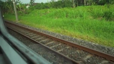 Pencere kenarında oturan trene bin. Pencerenin dışındaki raylara ve pirinç tarlalarına bak. Tren varış noktasına doğru hızla ilerliyor.