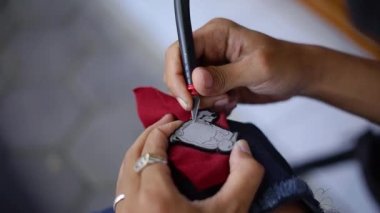 Emaye boyası kullanılarak yapılan akrilik ve renkte iğne yapma süreci, temizlik, boya, cilalama ve boyama süreçleri zanaatkarlar tarafından yapılır.