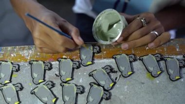 Emaye boyası kullanılarak yapılan akrilik ve renkte iğne yapma süreci, temizlik, boya, cilalama ve boyama süreçleri zanaatkarlar tarafından yapılır.