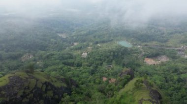 Sabahları Nglanggeran Antik Volkan eko eko alanının panoramik görüntüsü. Sakin bir atmosferi olan ve pirinç tarlaları ve köyleriyle çevrili kalın beyaz sisli bir dron kullanıyor.