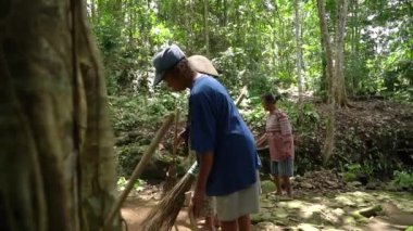 Köylüler, otların yetiştiği bahçelerini ve su kaynaklarını temizlemek için birlikte çalışırlar. Hem erkekler hem de kadınlar basit ve geleneksel aletlerle.
