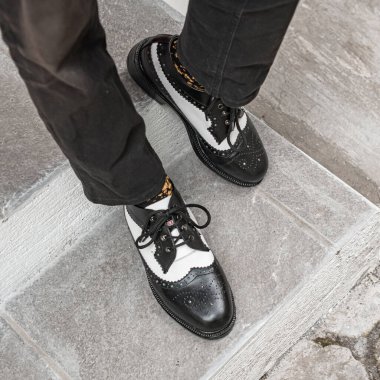 Genç adam klasik bir iki tonluk hakiki deri ayakkabı giydi. Parlak ve güneşli bir günde takılmaya hazır eski moda ayakkabılar..