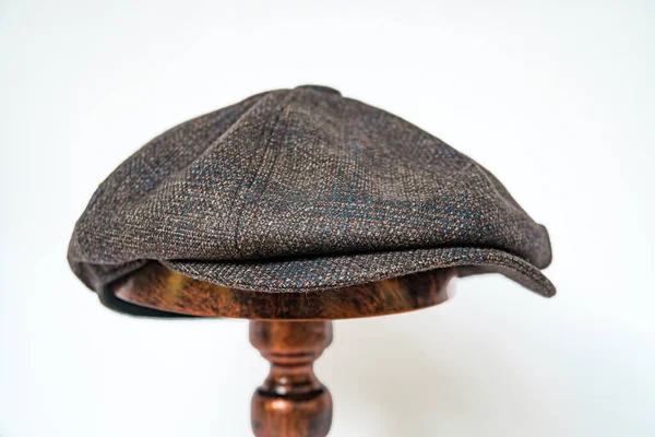 一种经典的八格报童帽的细节 这种帽子的背景是深褐色斜纹鲱鱼纹织物 镶嵌在白色背景的青铜人头上 — 图库照片