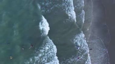 Güneşin kumsaldaki kumları yıkayan deniz dalgalarının üzerinde battığı güzel bir an. Doğu Aceh, Endonezya 'da bozulmamış bir sahilde gün batımının sinematik drone görüntüleri.