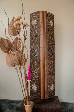 Boho tarzı oturma odasının içi, kurutulmuş çiçek şeklinde zarif aksesuarlarla ve pampa ya da kurutulmuş sazlık buketleri gibi beyaz bir duvar arka planıyla dekore edilen çiçeklerle dolu..