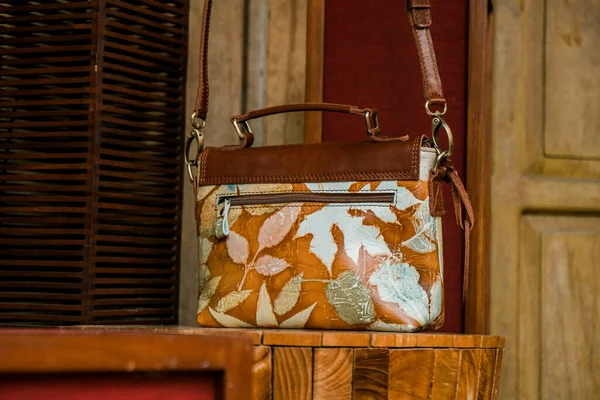 Display of leather bags for women made by craftsmen in Indonesia. Various types of detailed and beautiful women's bags are combined with eco print artwork with leaf and flower motifs