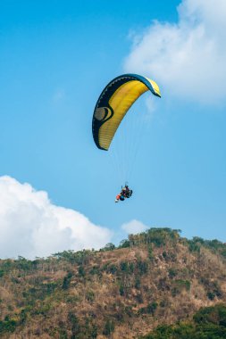Dağlık bölgelerde ve açık mavi gökyüzünde uçan paraglasyon cazibesi. Paragliding, gökyüzünde paraşütle uçarak adrenalin salgılayan bir spordur.