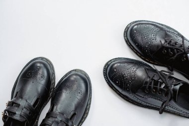 Klasik bir kanat ucu modeli ve parlak siyah bir Mary Jane mankeni olan iki çift erkek ve kadın ayakkabısı konsepti. Temiz beyaz arka planda el yapımı bir çift eski ayakkabının fotoğrafı.