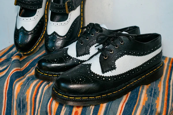 stock image Classic two-tone wingtip brogue shoes and two-tone Mary Jane shoes made of genuine leather displayed on brown cloth with a classic pattern. Concept photo of couple shoes with a vintage style