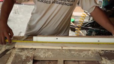 Basit bir ahşap atölyesinde çalışan bir marangozun kapağı. Atölye ahşap yığınları, dairesel testereler, çivi tabancaları, uçak makineleri, sondaj makineleri, ahşap yapıştırıcı ve hatta ahşap boyayla dolu.