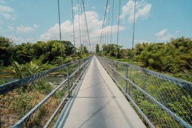 Sadece iki tekerlekli araçlar tarafından kullanılabilen ve sadece sırayla geçebilen bir asma köprü. Kırsal bölgelerdeki nehirleri bölen asma köprülerin toplum üzerinde çok olumlu bir etkisi vardır.