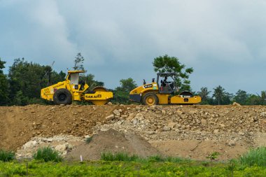 İki şehri birbirine bağlayan bir paralı yolun inşaatı için mekan. Gündüz boyunca proje alanından geçen kazıcılar, sıkıştırıcılar ve dozerler var