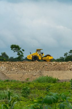 İki şehri birbirine bağlayan bir paralı yolun inşaatı için mekan. Gündüz boyunca proje alanından geçen kazıcılar, sıkıştırıcılar ve dozerler var