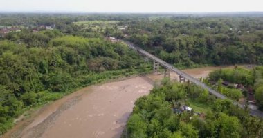 Endonezya 'nın Yogyakarta kentindeki Progo Nehri' nin hava görüntüleri. Çok büyük, kahverengi renkli ve bol kayalıklı. Yüksek uçurumlar ve sık ağaçlarla çevrili bir nehrin insansız hava aracı videosu