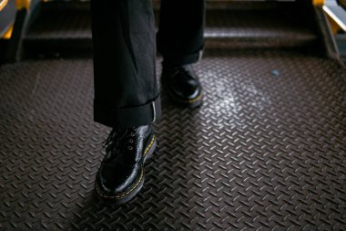 Terk edilmiş bir depoda erkek bir mankenin giydiği hakiki deriden yapılmış siyah kanat uçlu ayakkabıların yakın görüntüsü. Demirden yapılmış eski bir binada klasik kanat ucu ayakkabı konsepti.