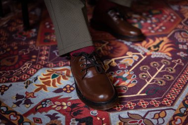 Klasik kırmızı halıda giyilen gerçek deriden yapılmış 3 delikli botların yakın çekimi. Türk kırmızı halısında kahverengi çizmeli resmi konsept fotoğraf