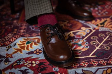 Klasik kırmızı halıda giyilen gerçek deriden yapılmış 3 delikli botların yakın çekimi. Türk kırmızı halısında kahverengi çizmeli resmi konsept fotoğraf