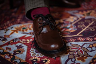 Klasik kırmızı halıda giyilen gerçek deriden yapılmış 3 delikli botların yakın çekimi. Türk kırmızı halısında kahverengi çizmeli resmi konsept fotoğraf