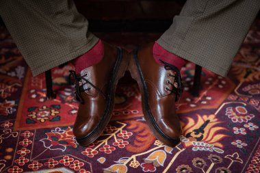 Klasik kırmızı halıda giyilen gerçek deriden yapılmış 3 delikli botların yakın çekimi. Türk kırmızı halısında kahverengi çizmeli resmi konsept fotoğraf