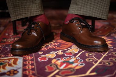 Klasik kırmızı halıda giyilen gerçek deriden yapılmış 3 delikli botların yakın çekimi. Türk kırmızı halısında kahverengi çizmeli resmi konsept fotoğraf