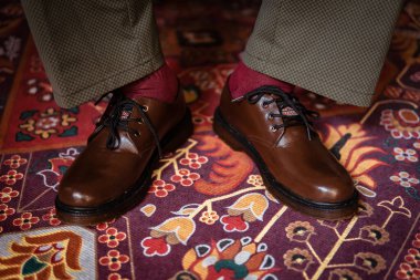 Klasik kırmızı halıda giyilen gerçek deriden yapılmış 3 delikli botların yakın çekimi. Türk kırmızı halısında kahverengi çizmeli resmi konsept fotoğraf