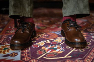 Klasik kırmızı halıda giyilen gerçek deriden yapılmış 3 delikli botların yakın çekimi. Türk kırmızı halısında kahverengi çizmeli resmi konsept fotoğraf