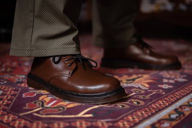 Klasik kırmızı halıda giyilen gerçek deriden yapılmış 3 delikli botların yakın çekimi. Türk kırmızı halısında kahverengi çizmeli resmi konsept fotoğraf