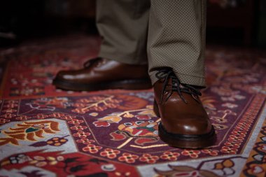 Klasik kırmızı halıda giyilen gerçek deriden yapılmış 3 delikli botların yakın çekimi. Türk kırmızı halısında kahverengi çizmeli resmi konsept fotoğraf