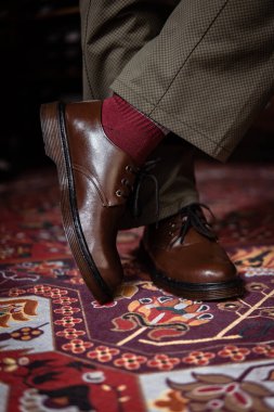 Klasik kırmızı halıda giyilen gerçek deriden yapılmış 3 delikli botların yakın çekimi. Türk kırmızı halısında kahverengi çizmeli resmi konsept fotoğraf
