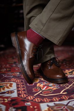 Klasik kırmızı halıda giyilen gerçek deriden yapılmış 3 delikli botların yakın çekimi. Türk kırmızı halısında kahverengi çizmeli resmi konsept fotoğraf