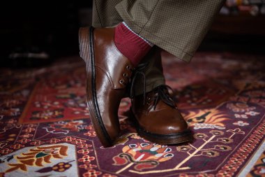 Klasik kırmızı halıda giyilen gerçek deriden yapılmış 3 delikli botların yakın çekimi. Türk kırmızı halısında kahverengi çizmeli resmi konsept fotoğraf