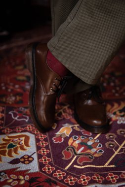 Klasik kırmızı halıda giyilen gerçek deriden yapılmış 3 delikli botların yakın çekimi. Türk kırmızı halısında kahverengi çizmeli resmi konsept fotoğraf