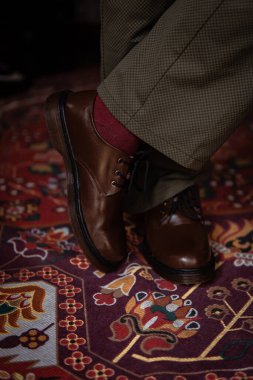Klasik kırmızı halıda giyilen gerçek deriden yapılmış 3 delikli botların yakın çekimi. Türk kırmızı halısında kahverengi çizmeli resmi konsept fotoğraf