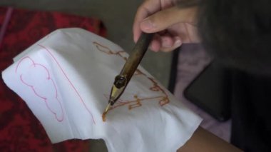 Katılımcıların tavada sıcak balmumu kullanarak geleneksel batik yapmayı öğrendikleri ve beyaz bir bez parçasına konan 4K görüntüler. Yeni başlayanların geleneksel Cava Batik resmini öğrenme süreci
