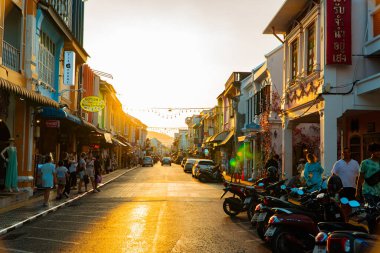 Günbatımının altın ışığı Phuket, Tayland 'daki yüz yıllık Çin-Portekiz kasaba evlerini aydınlatıyor. Eski şehirde güneş turistlerle dolu.