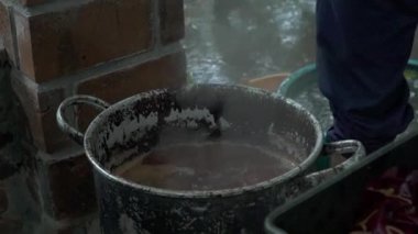 Katılımcıların geleneksel batik kumaşı boyamayı öğrenirken havuza boya bandırıp kaynar suya batırdıkları yavaş çekim görüntüleri. Yeni başlayanlar batik kumaşı geleneksel şekilde boyamayı öğrenirler.