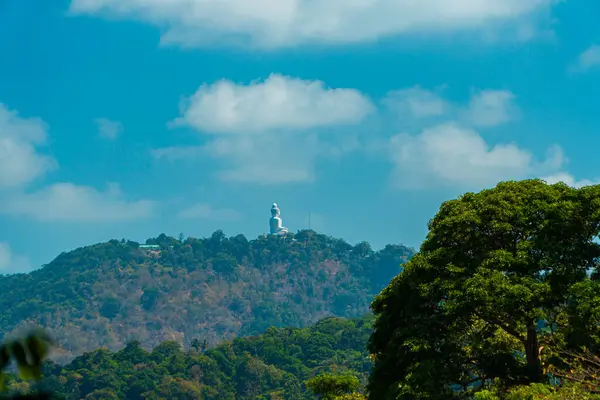 The Phuket Big Buddha statue made of white marble can be seen from a distance among the rows of green hills. Viewed from the top of the hill, Phuket\'s Big Buddha monument looks majestic and beautiful
