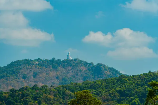 The Phuket Big Buddha statue made of white marble can be seen from a distance among the rows of green hills. Viewed from the top of the hill, Phuket\'s Big Buddha monument looks majestic and beautiful